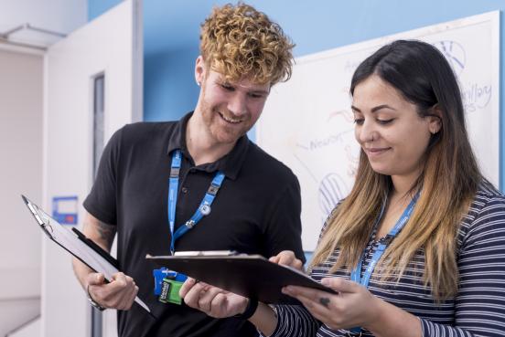 Man and woman, smiling, looking at clipboards